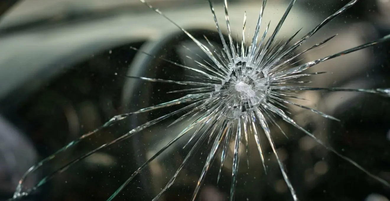 Gros plan sur un impact sur un pare-brise de voiture avec mise au point sélective illustrant la décision entre réparation et remplacement